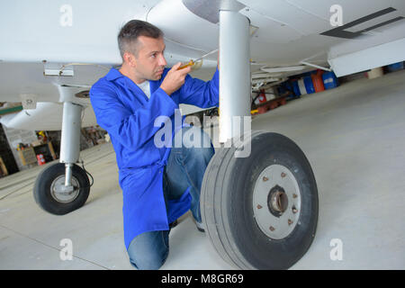Uomo che lavora sul lato inferiore del velivolo Foto Stock