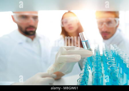 Immagine di sfondo è un gruppo di scienziati che studiano il liquido nel tubo di vetro. Foto Stock