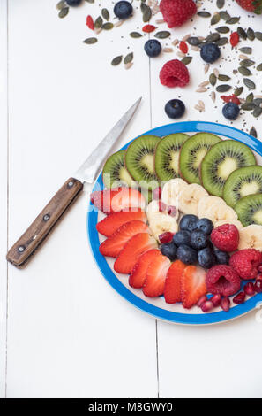 Piatto di frutta tagliata con semi su un bianco sullo sfondo di legno Foto Stock