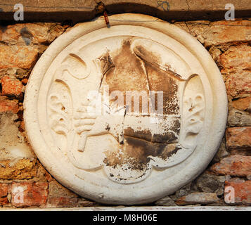 Emblema con un blindato mano che regge una mazza medievale, antico rilievo sulla parete in Venezia Foto Stock