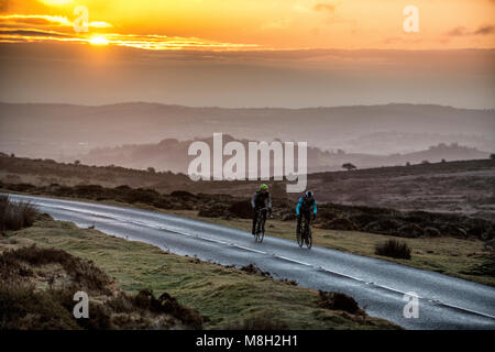 Due ciclisti su strada sulla strada passato Haytor su Dartmoor nel Devon a sunrise. Foto Stock