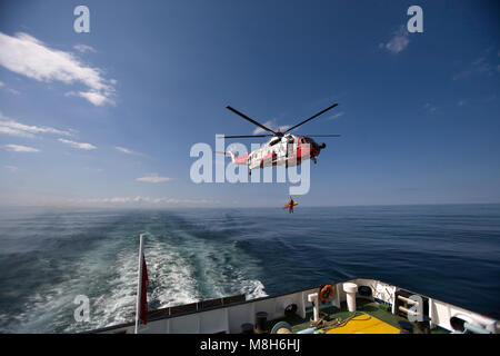 HM Guardia Costiera elicottero Sikorsky effettua una formazione in soccorso il Minch oltre il Caledonian Macbrayne Ulapool a Stornoway ferry. Foto Stock