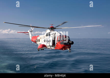 HM Guardia Costiera elicottero Sikorsky effettua una formazione in soccorso il Minch oltre il Caledonian Macbrayne Ulapool a Stornoway ferry. Foto Stock