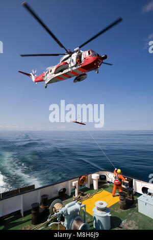 HM Guardia Costiera elicottero Sikorsky effettua una formazione in soccorso il Minch oltre il Caledonian Macbrayne Ulapool a Stornoway ferry. Foto Stock