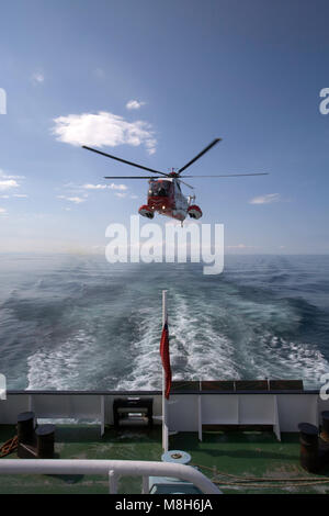 HM Guardia Costiera elicottero Sikorsky effettua una formazione in soccorso il Minch oltre il Caledonian Macbrayne Ulapool a Stornoway ferry. Foto Stock