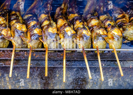 Pesci su spiedini fritti sono su un barbecue, barbeque, per la vendita al mercato di Nonthaburi Foto Stock