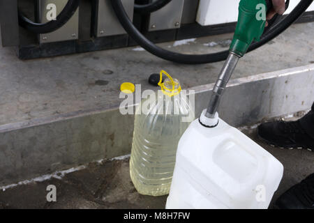 Uomo adulto si riempie di una vettura a benzina ad una stazione di benzina in inverno. il rifornimento di ugello uomo tenendo in mano, versando il liquido nel recipiente e fu Foto Stock