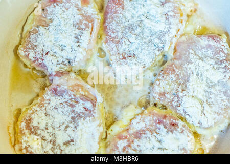 Cosce di pollo in pastella vengono fritte in padella. Foto Stock