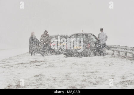 Long Bredy, Dorset, Regno Unito. Il 18 marzo 2018. Regno Unito Meteo. La gente fuori dei loro veicoli dopo un incidente che coinvolge 2 vetture che skidded fuori strada e colpire le barriere nella centrale di prenotazione durante condizioni di Blizzard sulla A35 a lunga Bredy tra Bridport e Dorchester nel Dorset come neve pesante che ha coperto la strada, rende la guida pericolosa. Credito Foto: Graham Hunt/Alamy Live News. Foto Stock