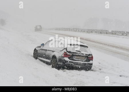 Long Bredy, Dorset, Regno Unito. Il 18 marzo 2018. Regno Unito Meteo. Un auto abbandonate in condizioni di bufera di neve sulla A35 a lunga Bredy tra Bridport e Dorchester nel Dorset come neve pesante che ha coperto la strada, rende la guida pericolosa. Credito Foto: Graham Hunt/Alamy Live News. Foto Stock