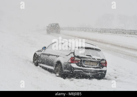 Long Bredy, Dorset, Regno Unito. Il 18 marzo 2018. Regno Unito Meteo. Un auto abbandonate in condizioni di bufera di neve sulla A35 a lunga Bredy tra Bridport e Dorchester nel Dorset come neve pesante che ha coperto la strada, rende la guida pericolosa. Credito Foto: Graham Hunt/Alamy Live News. Foto Stock