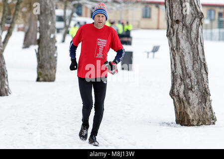 Chippenham, Regno Unito, 18 marzo, 2018. La neve non riesce a fermare un runner godendo la sua domenica mattina eseguito in Chippenham, Wiltshire. Credito: lynchpics/Alamy Live News Foto Stock