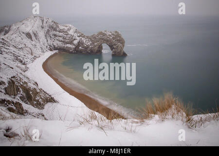 Il 18 marzo 2018. Una sorprendente serie di bufera di neve spazzato tutta la contea del Dorset per tutta la notte e la mattina. La bellissima formazione rocciosa naturale, porta di Durdle situato su Jurassic Coast è coperto in una spolverata di neve. Nevica raramente nel Dorset, e questo anno ha nevicato due volte in una quindicina di giorni. Credito: Wayne Farrell/Alamy News Foto Stock