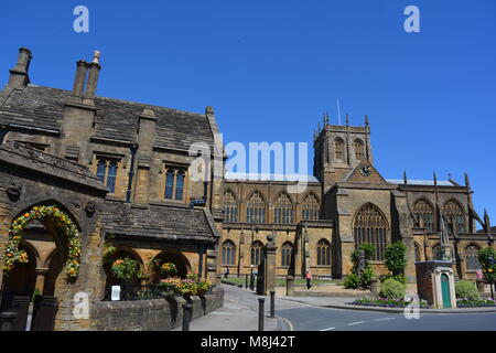 L'esterno Chiesa Abbaziale di Santa Maria Vergine a Sherborne, Dorset, usualmente noto come Sherborne Abbey con St Johns Almshouse in primo piano. Foto Stock