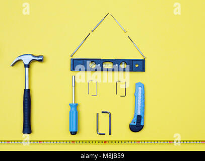 Selezione di strumenti a forma di casa home improvement concetto su sfondo giallo. Foto Stock