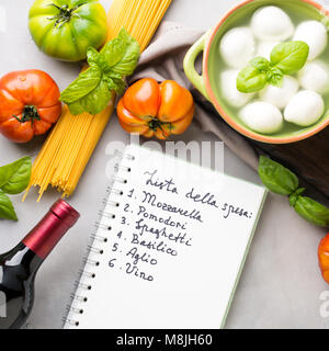 La pasta, il pomodoro, la mozzarella ancora vita sul grigio sfondo rustico. Prodotti tradizionali e cibo lista della spesa per gli spaghetti con i pomodori in italiano Foto Stock