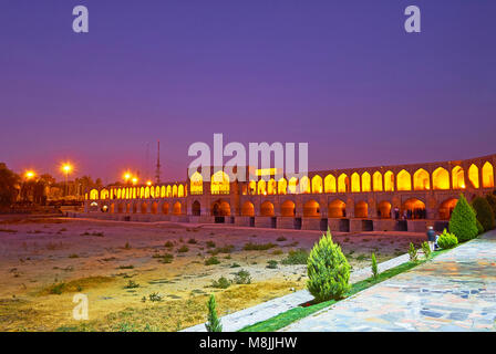 La passeggiata serale in Moshtagh-e Aval Park, stretching lungo la riva del fiume Zayandeh, con vista sul pittoresco ponte Khaju, Isfahan, Iran. Foto Stock