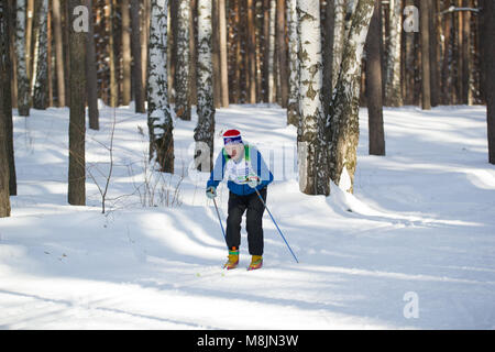 KAZAN, RUSSIA - Marzo 2018: il vecchio uomo correre la maratona di sci nella soleggiata foresta congelati Foto Stock