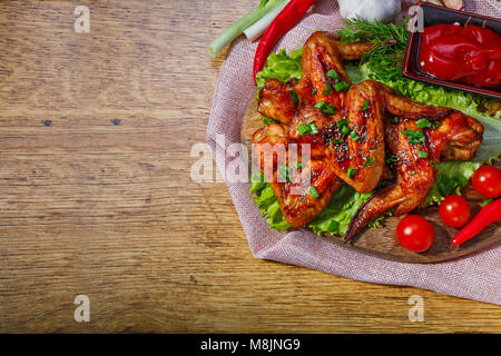 Alette di pollo fritte e verdure fresche sulla tavola di legno, con spazio per il testo Foto Stock