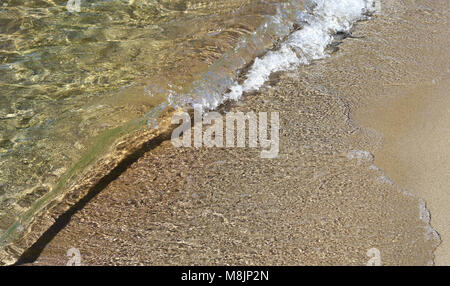 Onda morbida rotoli sulla riva sabbiosa Foto Stock