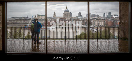 Un paio di studiare una schematica e prendere in vista dalla Tate Modern oltre il Tamigi che mostra Foster's Millennium Bridge e Wren's St Pauls Cathedral Foto Stock