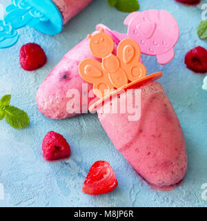 I gelati dei bambini e popsicles (rasberry sorbetto) blu su sfondo di calcestruzzo. Foto Stock