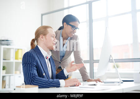 Imprenditore mostrando qualcosa su di uno schermo per il suo collega in un ufficio Foto Stock