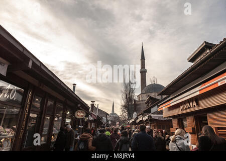 SARAJEVO, BOSNIA ERZEGOVINA - 17 febbraio 2018: strada affollata di turisti e un minareto della moschea nel quartiere Bascarsija d'inverno. Bascars Foto Stock