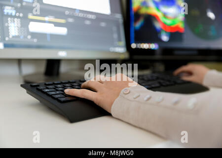 Femmina editor video funziona con i filmati sul suo personal computer, lavora in ufficio creative studio. Editing di video Foto Stock