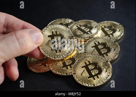 Cumulo di bitcoins con una moneta bitcoin in mano Foto Stock