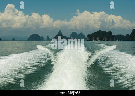 Wake generato in acqua dalla barca lasciando dietro le isolette calcaree della Baia di Phang Nga Thailandia Foto Stock