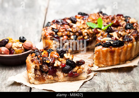 Deliziosa torta con frutta secca e i dadi sul vecchio tavolo in legno Foto Stock