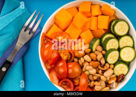 Una sana Vegana Vegetariana o patata dolce e fagioli Hawaiian stile Budda ciotola contro uno sfondo blu Foto Stock