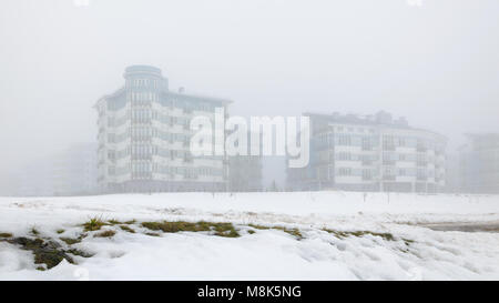 Paesaggio mistico della zona residenziale di basse case nella fitta nebbia Foto Stock