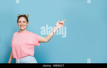 Moderno e giovane donna di puntamento spazio copia e sorridente Foto Stock