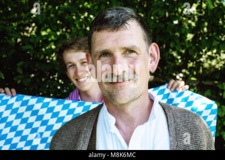 Ritratto di bello uomo vecchio e giovane azienda fino la bavarese di colori blu e bianco Foto Stock