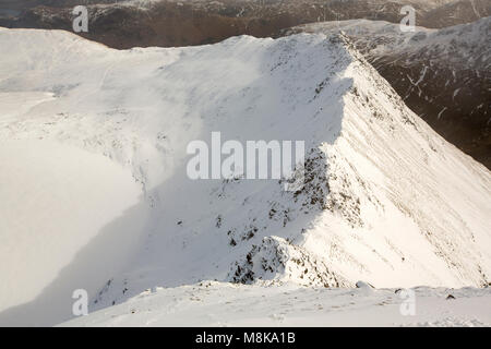 Guardando verso il basso a bordo di estensione su Helvellyn, Lake District, UK con un congelati, neve coperto Rosso Tarn. Foto Stock