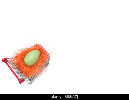 Acquisto di un uovo di pasqua dal supermercato, uovo di Pasqua nel carrello, shoping carrello isolato su sfondo bianco nest erba Foto Stock