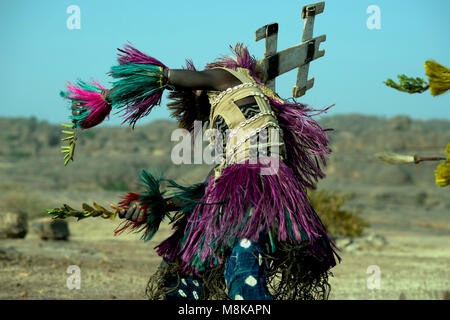 Un uomo Dogon colpi di scena e svolte mentre indossa una maschera di grandi dimensioni e copricapo e esecuzione di una tradizionale danza tribale. Paese Dogon del Mali, Africa occidentale. Foto Stock