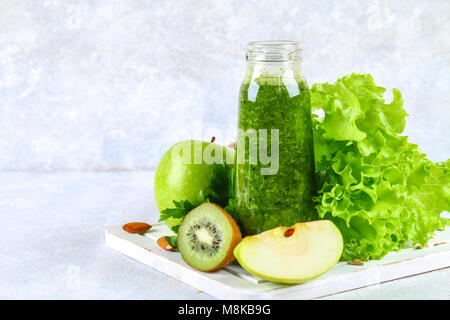 Frullati verde da prezzemolo, insalata, kiwi, Apple in una bottiglia su un calcestruzzo di colore grigio nella tabella Foto Stock