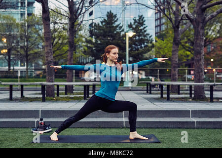 La donna caucasica esegue lo Yoga in un pubblico di New York City Park Foto Stock