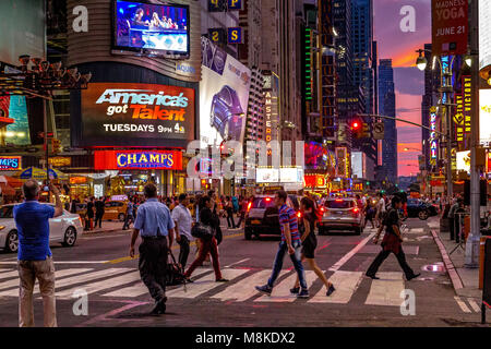 Persone su un attraversamento pedonale vicino a Times Square come thne sun imposta su Manhattan ,New York Foto Stock