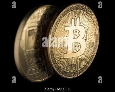 Due Golden bitcoins su uno sfondo nero, closeup. denaro elettronico Foto Stock