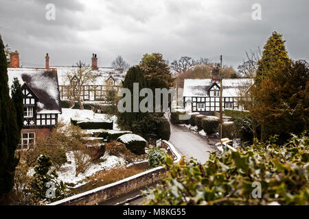 Coperta di neve in bianco e nero la metà case con travi di legno nel pittoresco villaggio di Cheshire di Barthomley England Regno Unito durante il periodo invernale Foto Stock