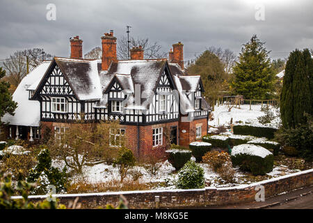 Coperta di neve in bianco e nero la metà case con travi di legno nel pittoresco villaggio di Cheshire di Barthomley England Regno Unito durante il periodo invernale Foto Stock