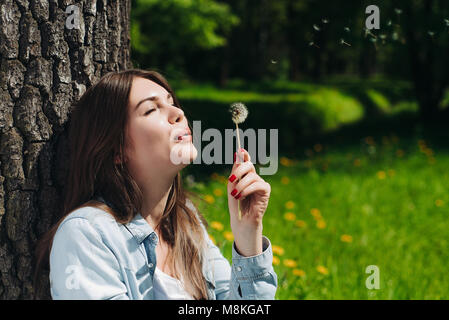 Bella giovane donna con il bianco tarassaco in posizione di parcheggio Foto Stock