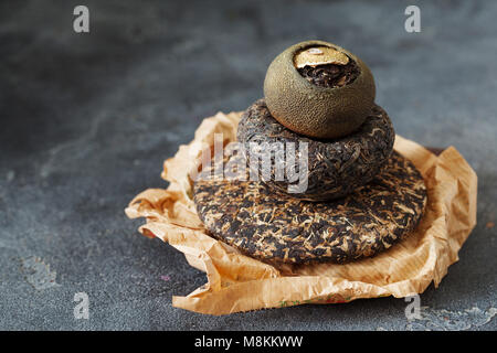 Asian premuto Pu-erh tè e shu Pu'er in mandarino su ardesia scuro dello sfondo spazio di copia Foto Stock