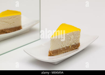 Un pezzo di Cheesecake al limone su una piastra bianca. La riflessione nello specchio. Foto Stock