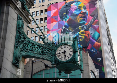 Oltre cento-anno-vecchio Marshall Fields orologi e un più recente murale di Blues grandi acque fangose su State Street a Chicago. Foto Stock