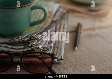 Quotidiani e tazze da caffè su tavole di legno. Foto Stock